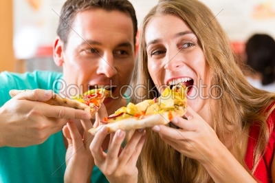 Man and woman eating a pizza