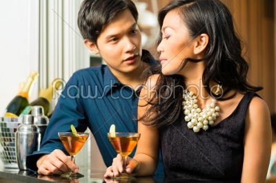 Man and woman in asia at bar with cocktails