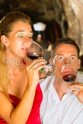 Man and woman tasking wine in cellar