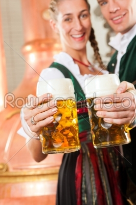 Man and woman with beer glass in brewery