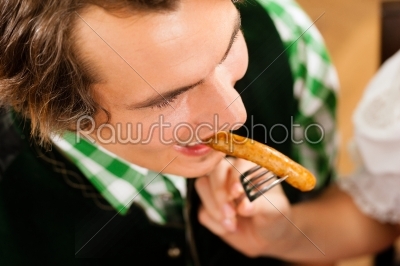 Man in restaurant or pub eating sausage