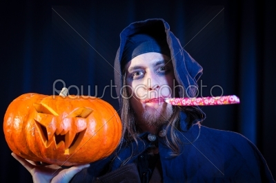 Man in scary Halloween costume holding pumpkin