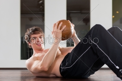 Man is exercising with medicine ball in gym