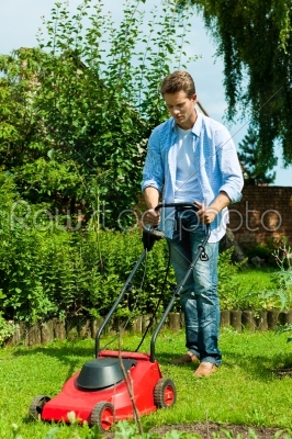Man is mowing the lawn in summer