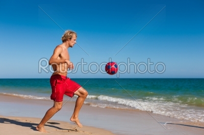 Man on beach playing soccer