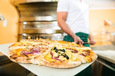 Man pushing the finished pizza from the oven