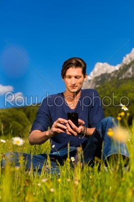 man with phone  sitting in the mountains 