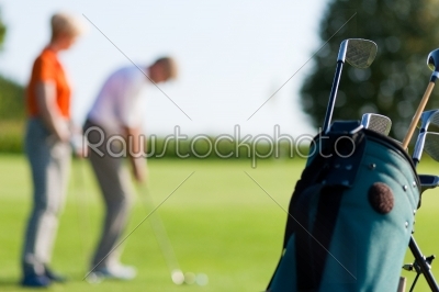 Mature couple playing Golf (focus on bag)