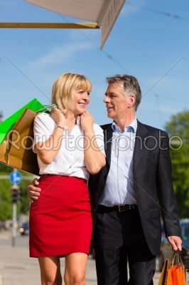 Mature couple strolling through city shopping in spring