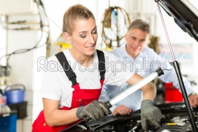 Mature man and female car mechanic in workshop