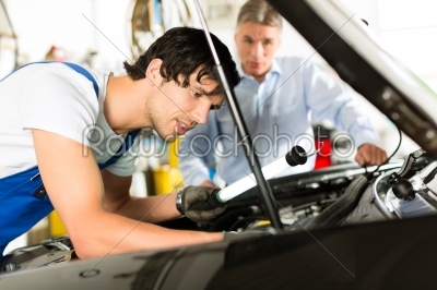 Mature man and mechanic looking at car engine 