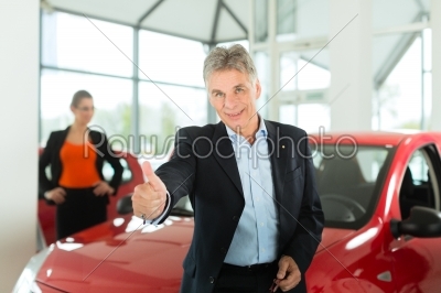 Mature man with woman and auto in car dealership