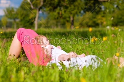 Mother playing with baby on meadow