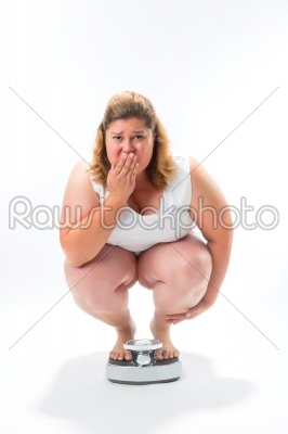 Obese young woman crouching on a scale