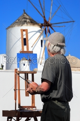 Painter artist paints a picture of Santorini