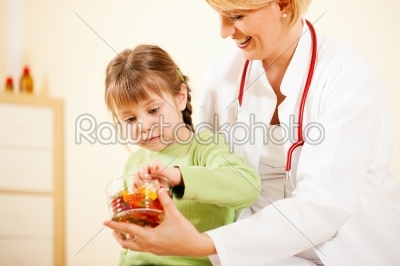 Pediatrician doctor giving candy to little patient