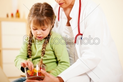 Pediatrician doctor giving candy to little patient