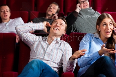 people in cinema theater with mobile phone