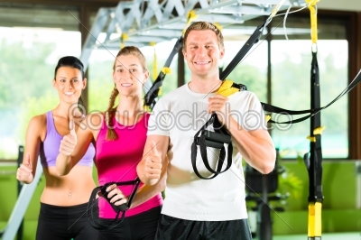 People in sport gym on suspension trainer