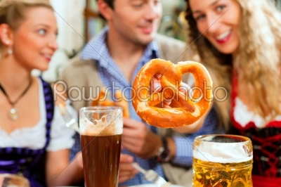 People with beer and pretzel in Bavarian pub