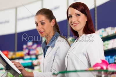 Pharmacist with assistant in pharmacy
