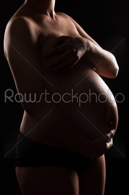 Pregnant woman naked touching her belly or  baby bump