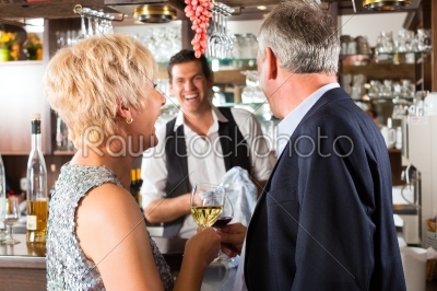 Senior couple at bar with glass of wine in hand