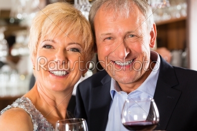 Senior couple at bar with glass of wine in hand