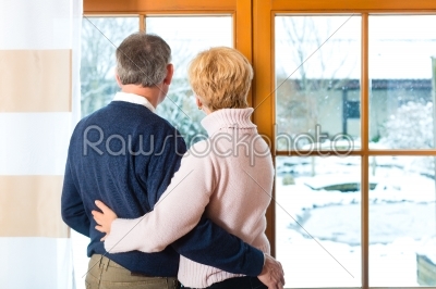 Senior couple looking or of the window hugging