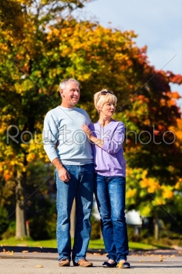 Seniors in autumn or fall walking hand in hand