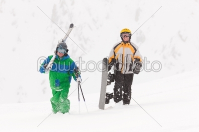 Skier and snowboarder carrying gear