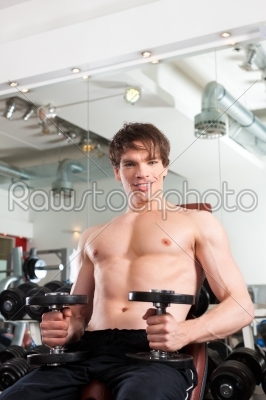 Sport - man is exercising with barbell in gym