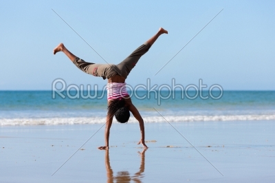 Sportive woman doing gymnastics on the beach