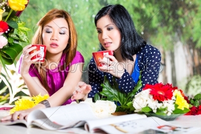 Two Asian girlfriends with fashion magazine