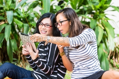 Two Asian girlfriends with tablet computer