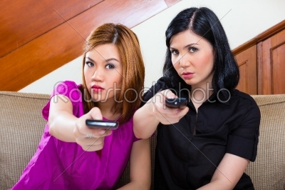 Two asian girls at home watching TV