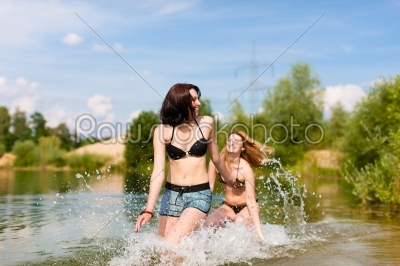 Two happy women having fun at lake in summer