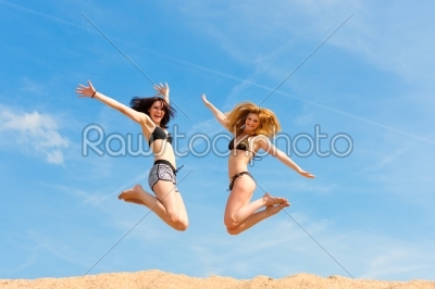 Two happy women jumping high with fun