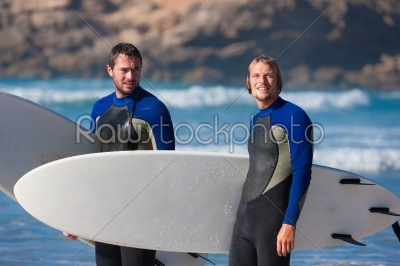 Two surfers with their surf boards standing on the beach