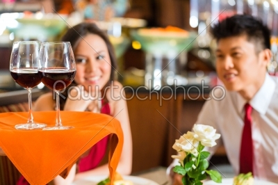 Waiter serving Chinese couple red wine in fancy restaurant