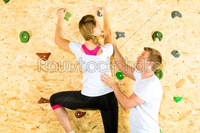 Woman and man climbing at climbing wall