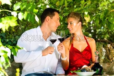 Woman and man sitting under grapevine and drinking