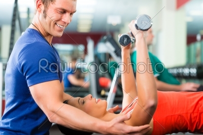 woman and Personal Trainer in gym, with dumbbells