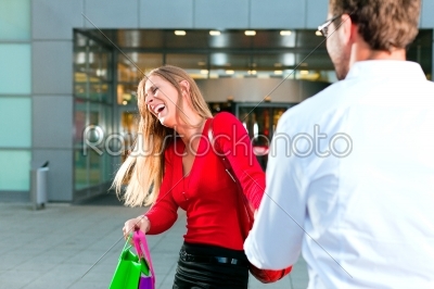 Woman dragging man into shopping mall