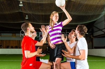 Woman has a football in hand, men kneeling down