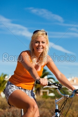 Woman in holidays cycling under a blue sky