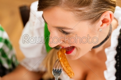 Woman in restaurant or pub eating sausage