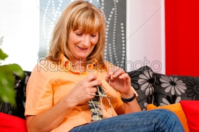 Woman is knitting in her living room