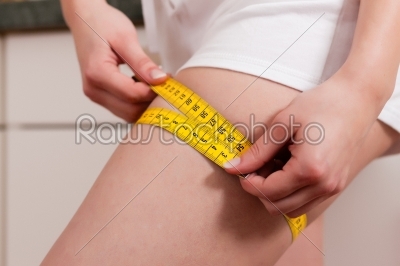 Woman measuring thigh with tape