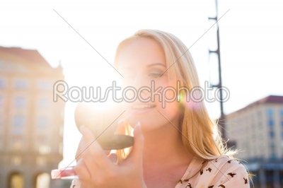 Woman refreshing makeup with gloss in the sun